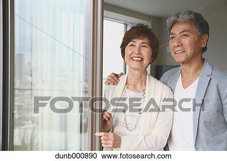 Stock Image - Fashionable Japanese senior couple by the window. Fotosearch