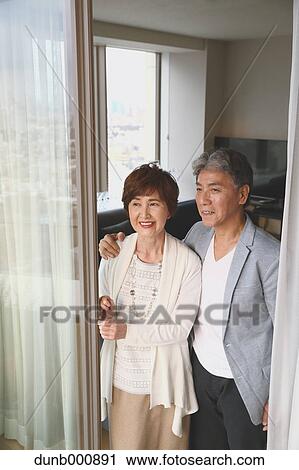 Stock Image - Fashionable Japanese senior couple by the window. Fotosearch