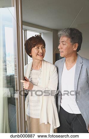 Stock Photo - Fashionable Japanese senior couple by the window. Fotosearch