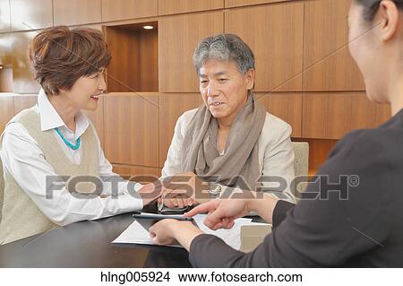 Picture - Fashionable Japanese senior couple discussing with advisor. Fotosearch