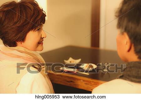 Stock Image - Fashionable Japanese senior couple having a good time at the restaurant. Fotosearch
