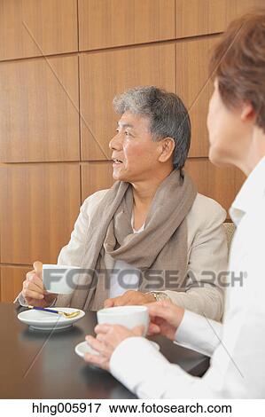 Stock Photo - Fashionable Japanese senior couple enjoying a cup of coffee. Fotosearch