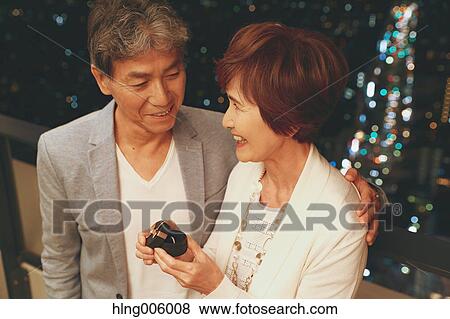 Stock Photo - Fashionable Japanese senior couple celebrating with Tokyo cityscape in the background. Fotosearch