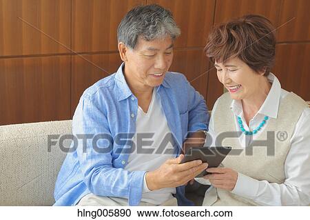Fashionable Japanese senior couple with tablet on sofa View Large Photo Image Stock Image - Fashionable Japanese senior couple with tablet on sofa. Fotosearch