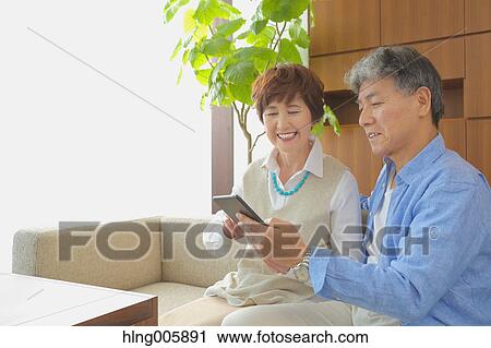 Fashionable Japanese senior couple with tablet on sofa View Large Photo Image Stock Image - Fashionable Japanese senior couple with tablet on sofa. Fotosearch
