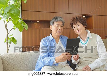 Fashionable Japanese senior couple with tablet on sofa View Large Photo Image Stock Photo - Fashionable Japanese senior couple with tablet on sofa. Fotosearch