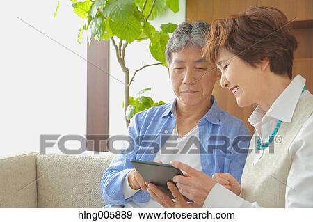 Fashionable Japanese senior couple with tablet on sofa View Large Photo Image Stock Photo - Fashionable Japanese senior couple with tablet on sofa. Fotosearch