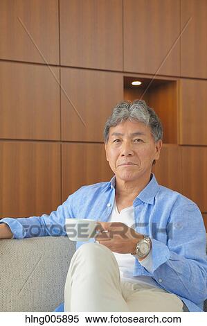 Fashionable Japanese senior man having a cup of coffee on the sofa View Large Photo Image Stock Photography - Fashionable Japanese senior man having a cup of coffee on the sofa. Fotosearch