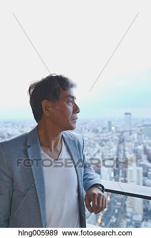 Stock Photo - Fashionable Japanese senior man looking at Tokyo cityscape. Fotosearch