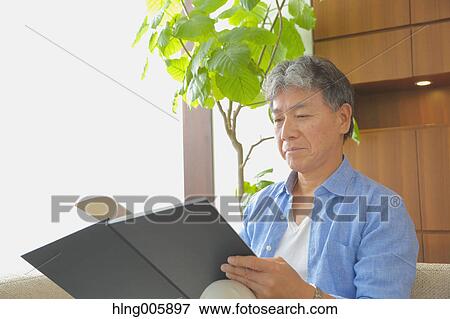Stock Photo - Fashionable Japanese senior man reading book. Fotosearch