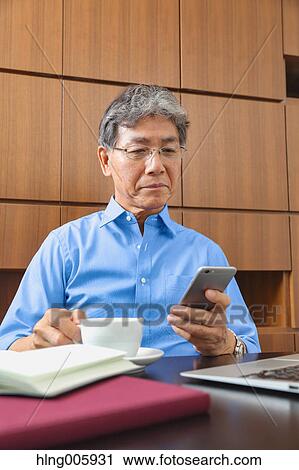 Stock Image - Fashionable Japanese senior man working. Fotosearch