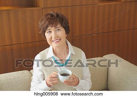 Fashionable Japanese senior woman having a cup of coffee on the sofa View Large Photo Image Stock Photo - Fashionable Japanese senior woman having a cup of coffee on the sofa. Fotosearch