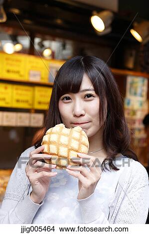 Picture - Fashionable Japanese woman eating bread at a traditional shopping street, Tokyo, Japan. Fotosearch