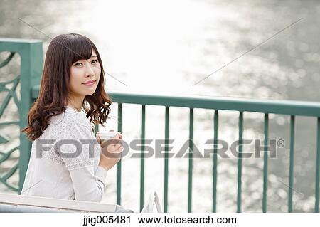 Fashionable Japanese woman with coffee sitting on a bench by the river, Tokyo, Japan View Large Photo Image Stock Image - Fashionable Japanese woman with coffee sitting on a bench by the river, Tokyo, Japan. Fotosearch