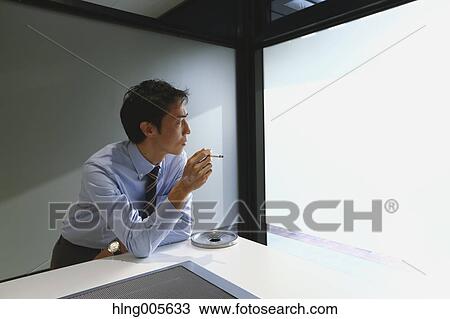 Stock Image - Japanese businessman in smoking room. Fotosearch