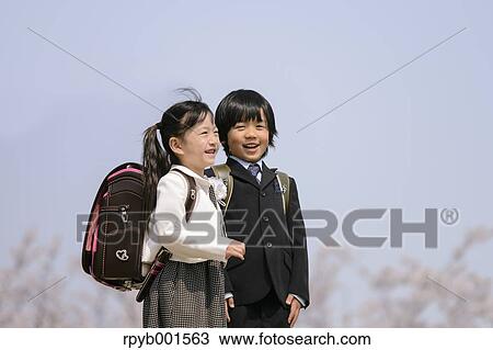 Stock Image - Japanese elementary school students and cherry blossoms. Fotosearch
