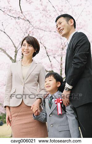 Stock Image - Japanese family with cherry blossoms in a city park. Fotosearch