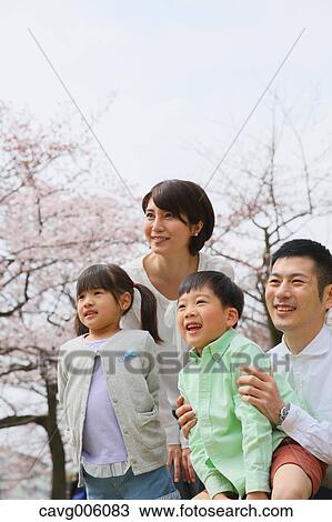Stock Image - Japanese family with cherry blossoms in a city park. Fotosearch