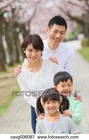 Stock Photo - Japanese family with cherry blossoms in a city park. Fotosearch