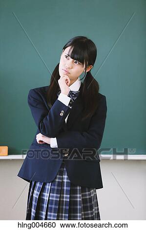 Stock Image - Japanese high-school student in front of classroom blackboard. Fotosearch