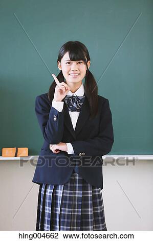 Stock Image - Japanese high-school student in front of classroom blackboard. Fotosearch