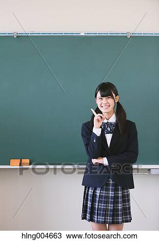 Stock Image - Japanese high-school student in front of classroom blackboard. Fotosearch