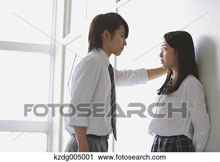 Stock Image - Japanese high-school students in a romantic moment in the school corridor. Fotosearch