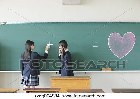 Picture - Japanese high-school students in front of classroom blackboard. Fotosearch