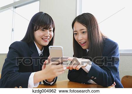 Stock Image - Japanese high-school students with smartphone in classroom. Fotosearch