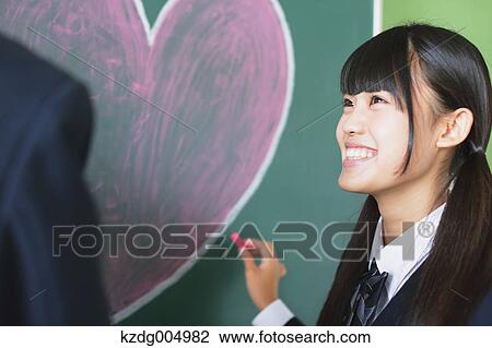 Stock Image - Japanese high-school students writing on classroom blackboard. Fotosearch