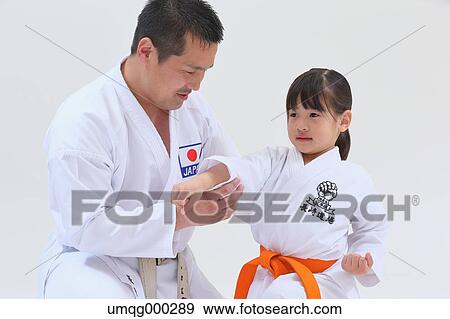 Stock Photo - Japanese kid in karate uniform training with teacher on white background. Fotosearch