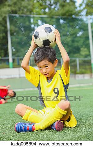 Picture - Japanese kid playing soccer. Fotosearch