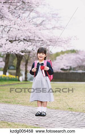 Stock Photo - Japanese kid with cherry blossoms in a city park. Fotosearch
