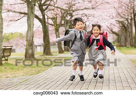 Stock Image - Japanese kids with cherry blossoms in a city park. Fotosearch
