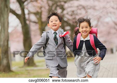 Stock Image - Japanese kids with cherry blossoms in a city park. Fotosearch