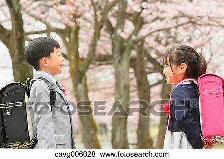 Stock Photo - Japanese kids with cherry blossoms in a city park. Fotosearch
