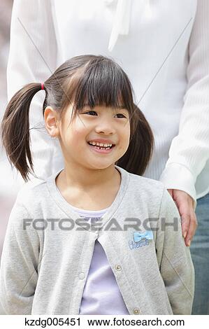 Stock Image - Japanese mother and daughter in a city park. Fotosearch