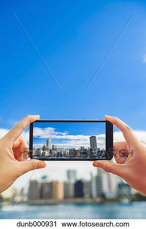 Stock Image - Japanese woman using augumented reality app on smartphone downtown Tokyo, Japan. Fotosearch
