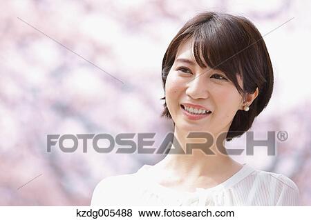 Stock Photo - Japanese woman with cherry blossoms in a city park. Fotosearch