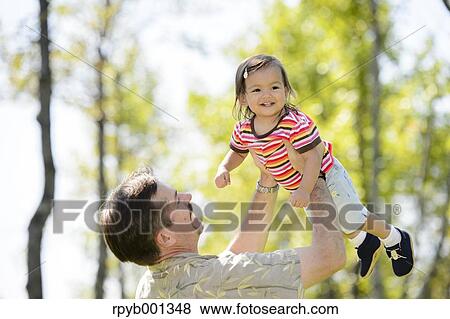 Kid and dad playing in a city park View Large Photo Image Stock Photo - Kid and dad playing in a city park. Fotosearch