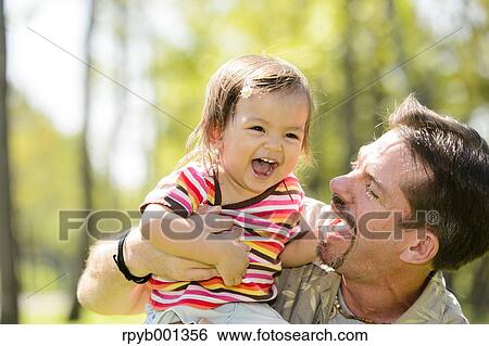 Kid and dad playing in a city park View Large Photo Image Stock Photograph - Kid and dad playing in a city park. Fotosearch