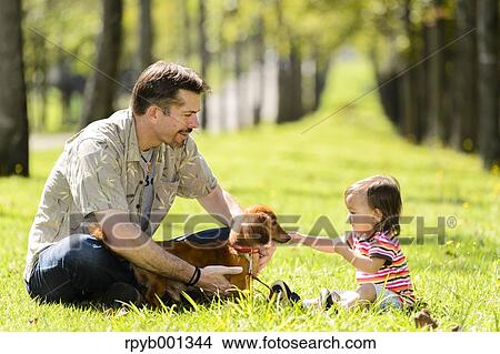 Kid and dad playing with dog in a city park View Large Photo Image Picture - Kid and dad playing with dog in a city park. Fotosearch