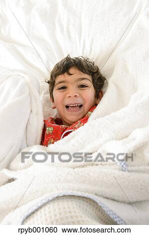 Stock Image - Kid playing on bed in a pijama. Fotosearch