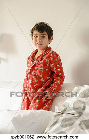 Stock Image - Kid playing on bed in a pijama. Fotosearch