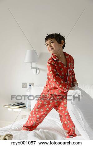 Stock Photo - Kid playing on bed in a pijama. Fotosearch