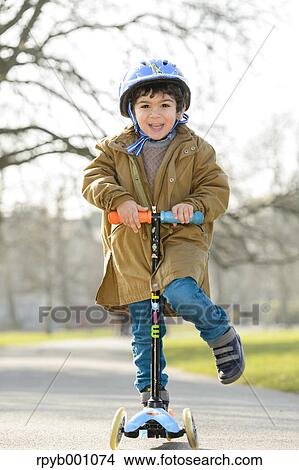 Picture - Kid playing with kickboard in a park. Fotosearch