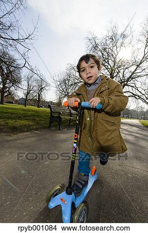 Picture - Kid playing with kickboard in a park. Fotosearch