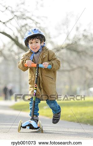 Stock Image - Kid playing with kickboard in a park. Fotosearch