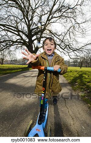 Stock Image - Kid playing with kickboard in a park. Fotosearch