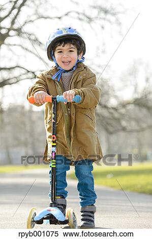 Stock Photography - Kid playing with kickboard in a park. Fotosearch
